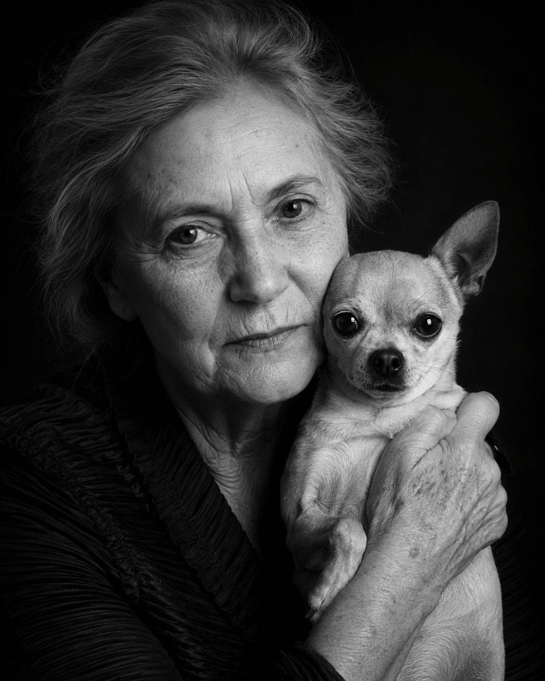Black-and-white studio portrait of a person beside their chihuahua